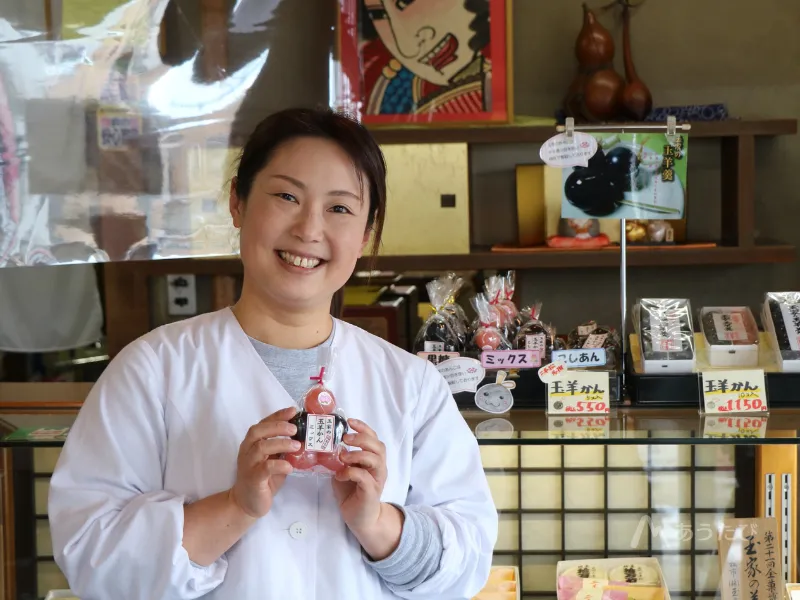 玉家玉振堂の店内で玉羊羹を手に笑顔を見せる渡邉史絵さん